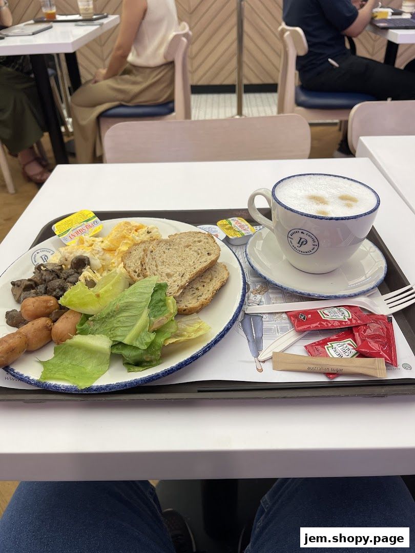 A breakfast tray with sausages, scrambled eggs, toast, salad, and a coffee at Délifrance.