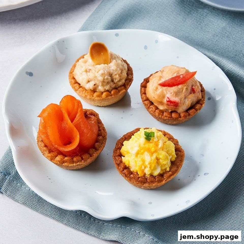 Four mini tarts with various savory fillings on a white plate.
