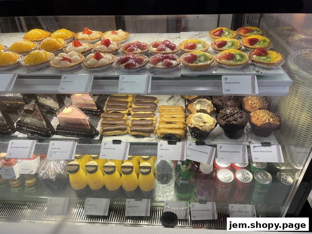 A display case filled with various pastries, cakes, muffins, and drinks from Délifrance.