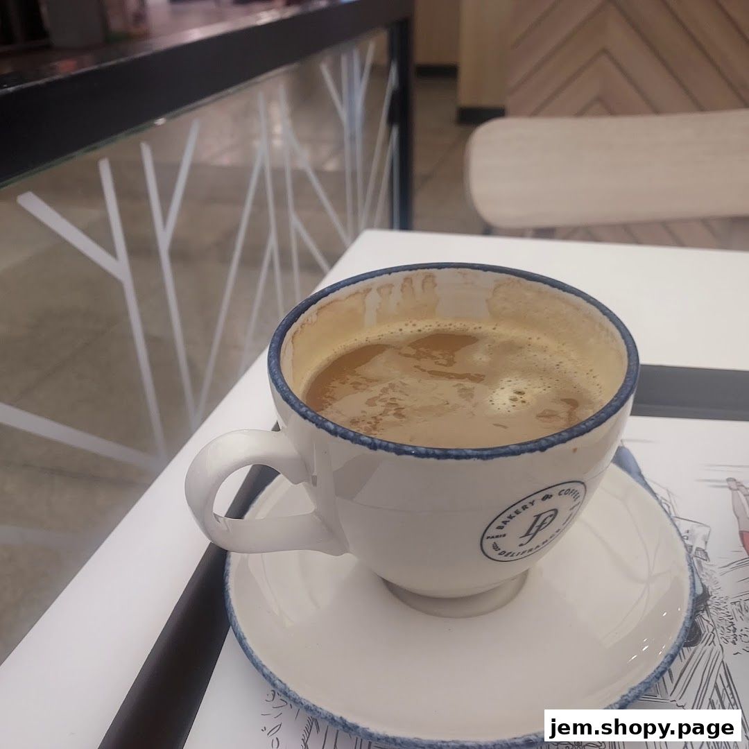 A cup of coffee sits on a saucer at Délifrance, with a blurred background.