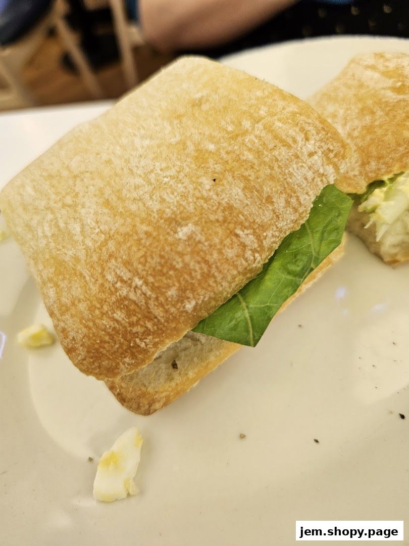 A close-up shot of a sandwich on a white plate with lettuce and bread.