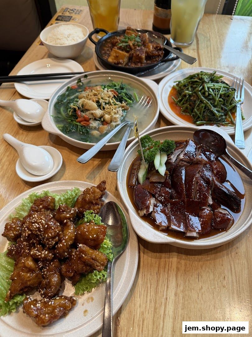 A table laden with various delicious Chinese dishes, including roasted duck and crispy chicken.