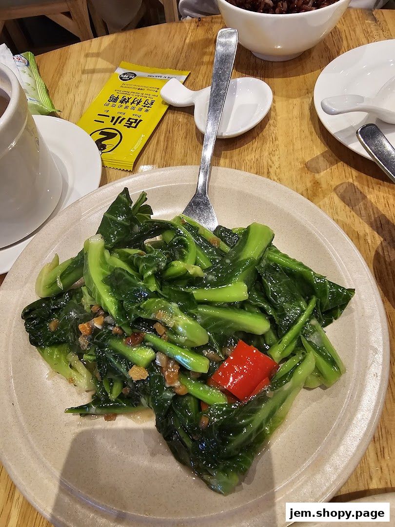 A plate of stir-fried Chinese broccoli with garlic and chili on a wooden table.