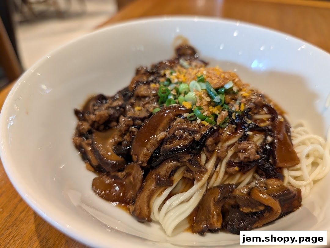 A bowl of noodles with minced meat and mushrooms, garnished with scallions.