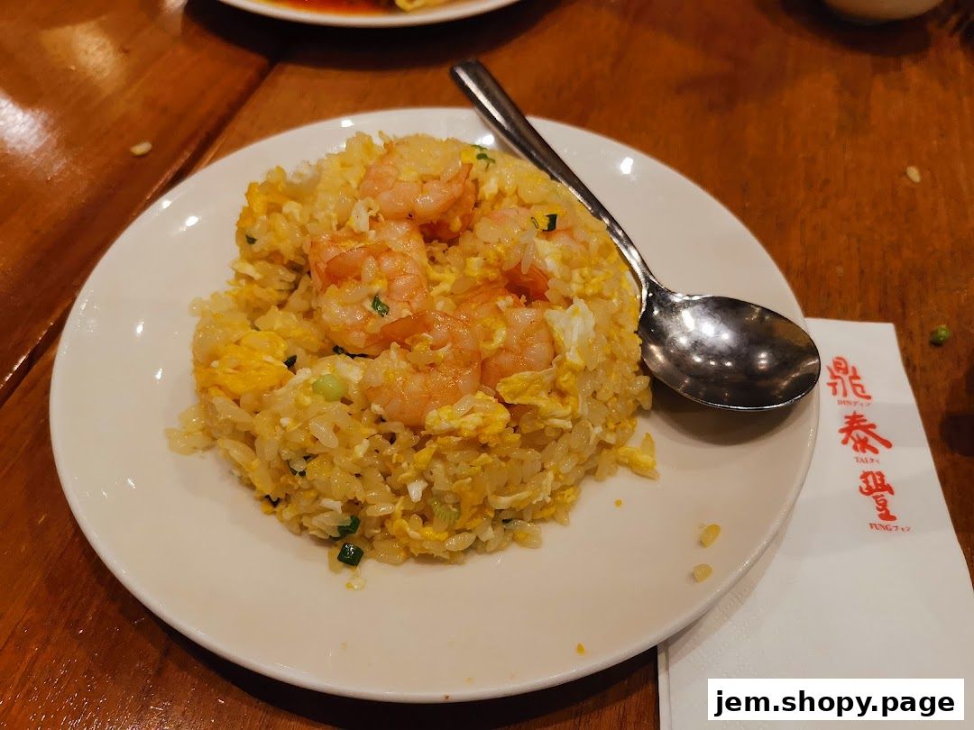A plate of shrimp fried rice with a spoon on a wooden table.