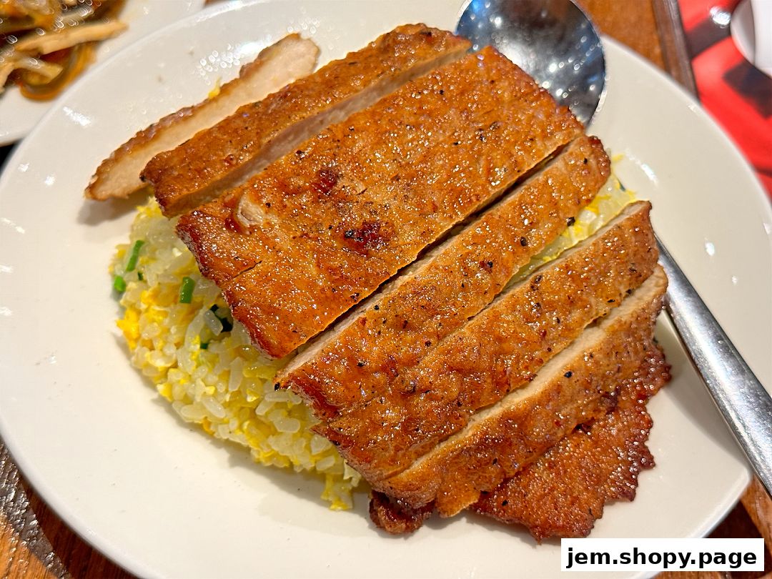 A plate of sliced pork chop served with fried rice and a spoon.