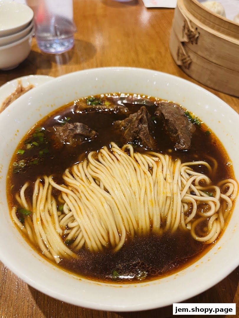 A close-up of a steaming bowl of beef noodle soup with tender beef chunks.