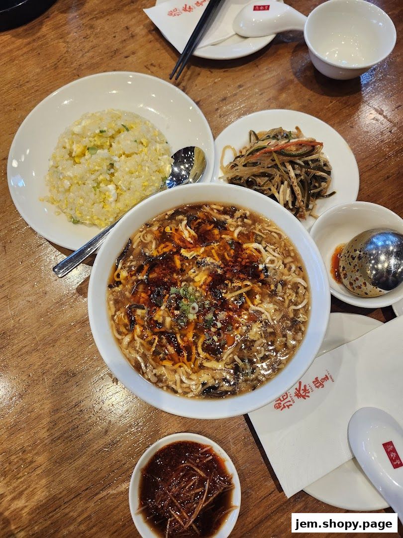 A table setting with a bowl of soup, fried rice, and side dishes at Din Tai Fung.