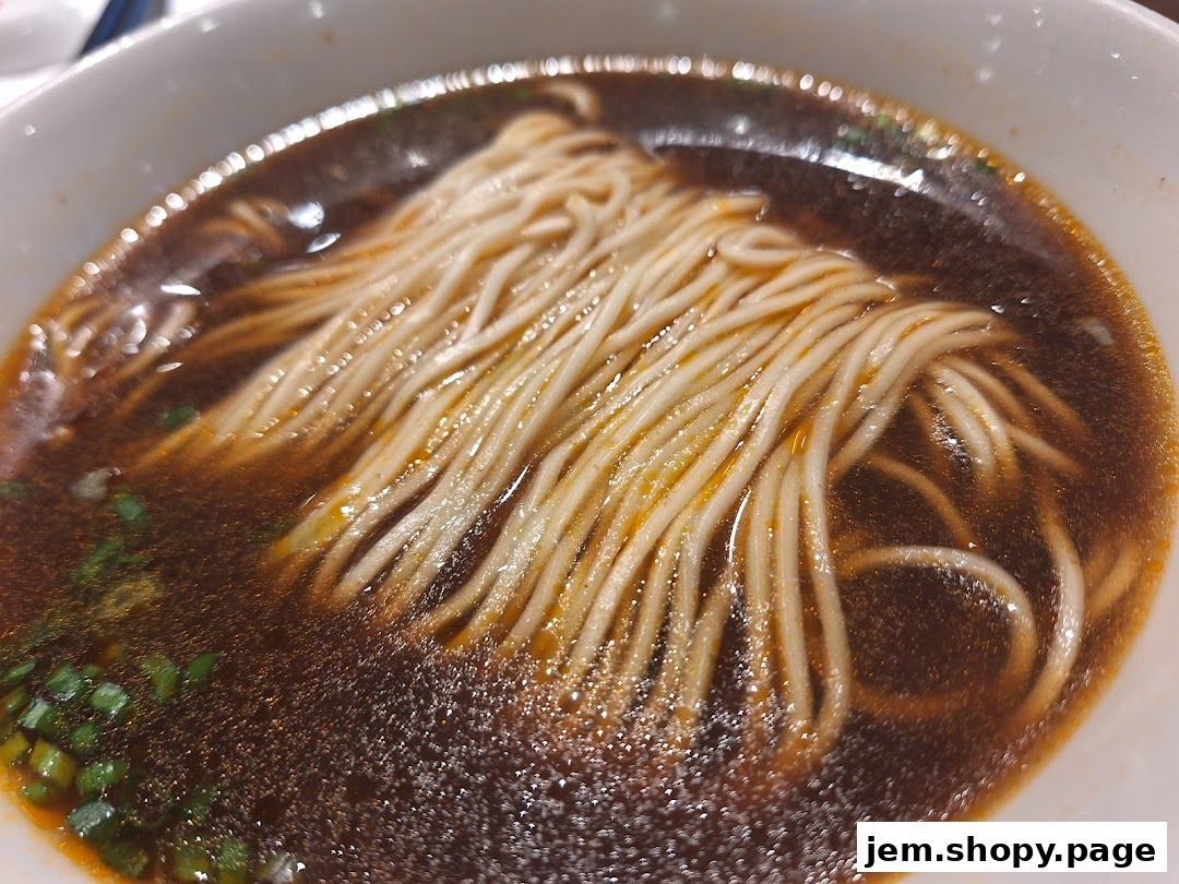 A close-up shot of a bowl of delicious noodle soup with chopped green onions.