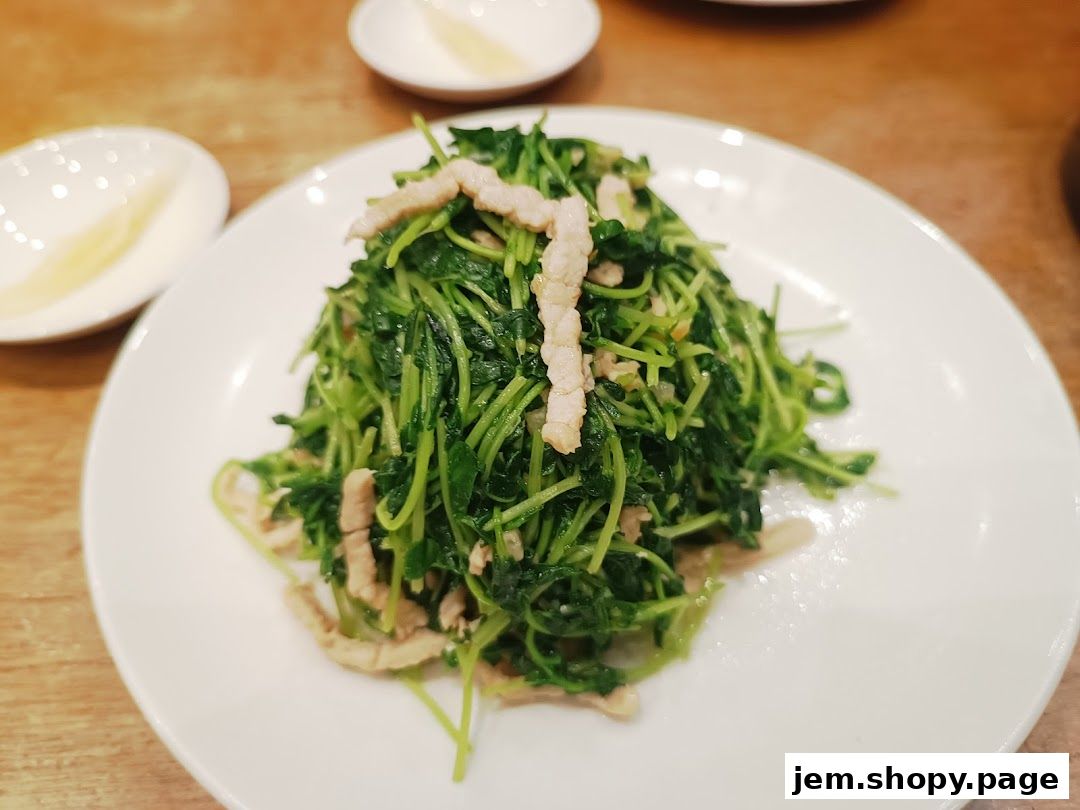 A plate of stir-fried pea shoots with thinly sliced pork.