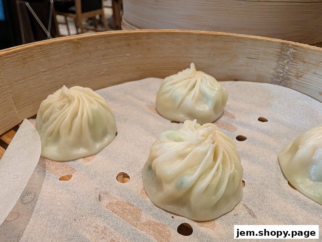 Steaming hot soup dumplings served in a bamboo steamer basket.