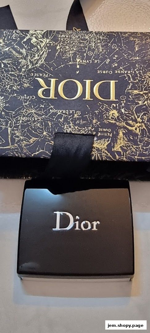 A black Dior compact sits before a dark blue box with gold constellation patterns.