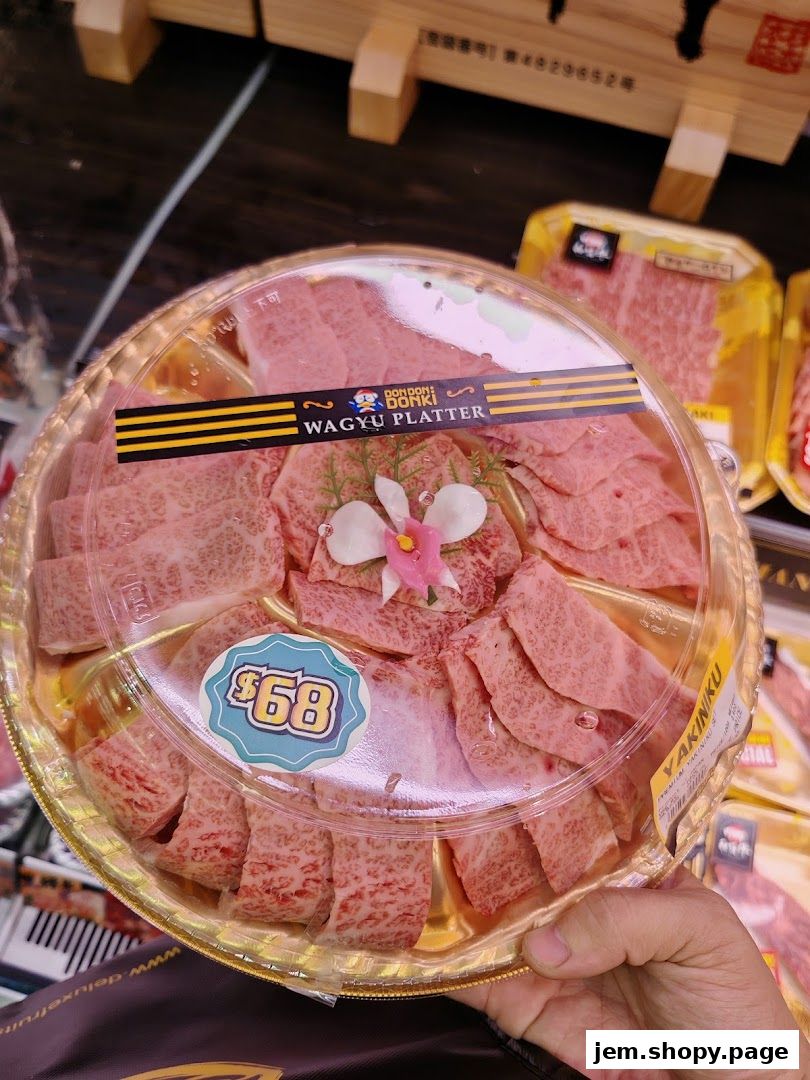 A hand holds a platter of premium wagyu beef slices, ready for yakiniku.