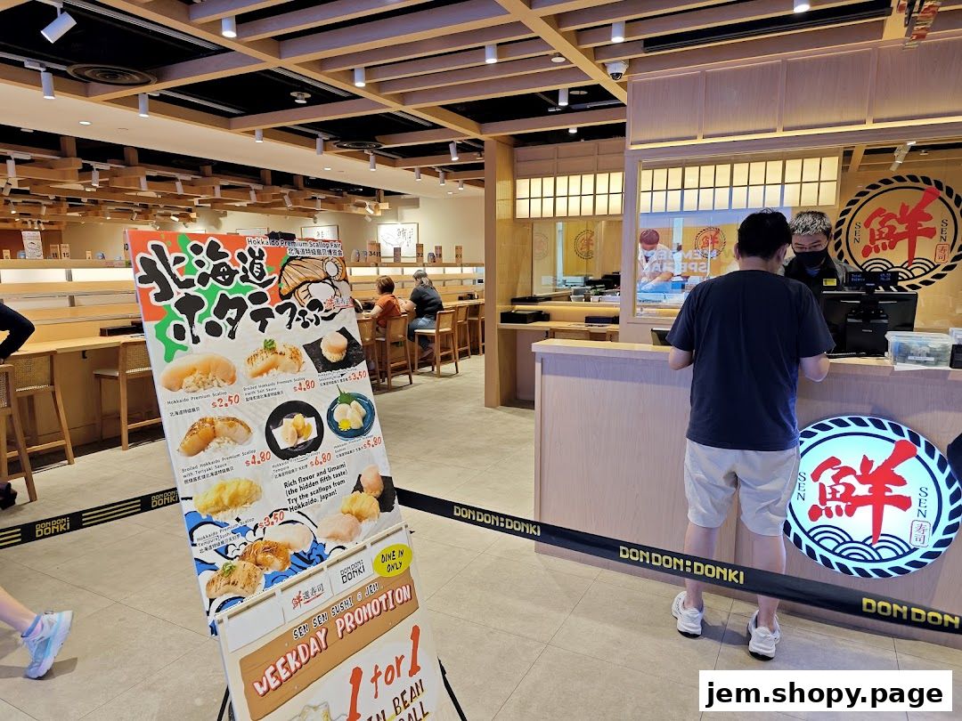 A promotional sign for a scallop fair is displayed at the entrance of a sushi restaurant.