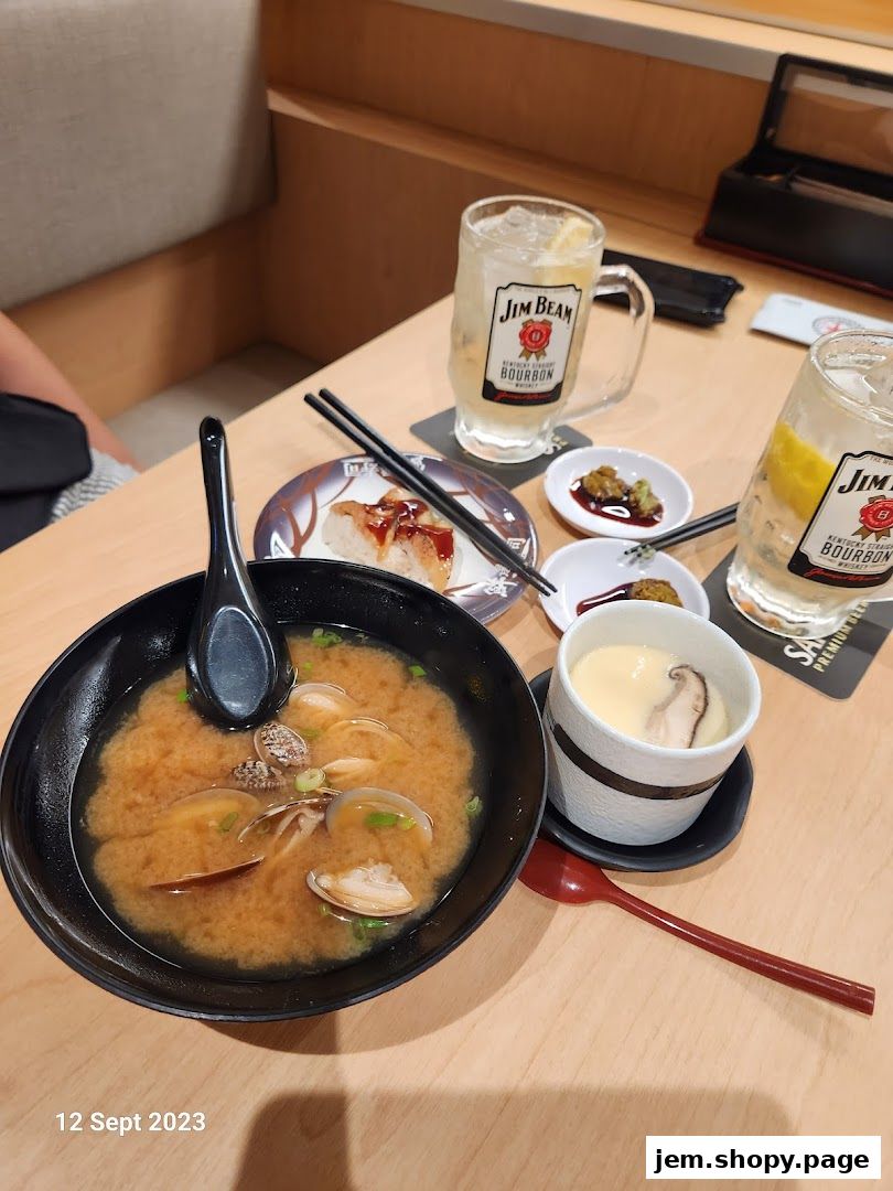 A table setting with miso soup, chawanmushi, sushi, and drinks.