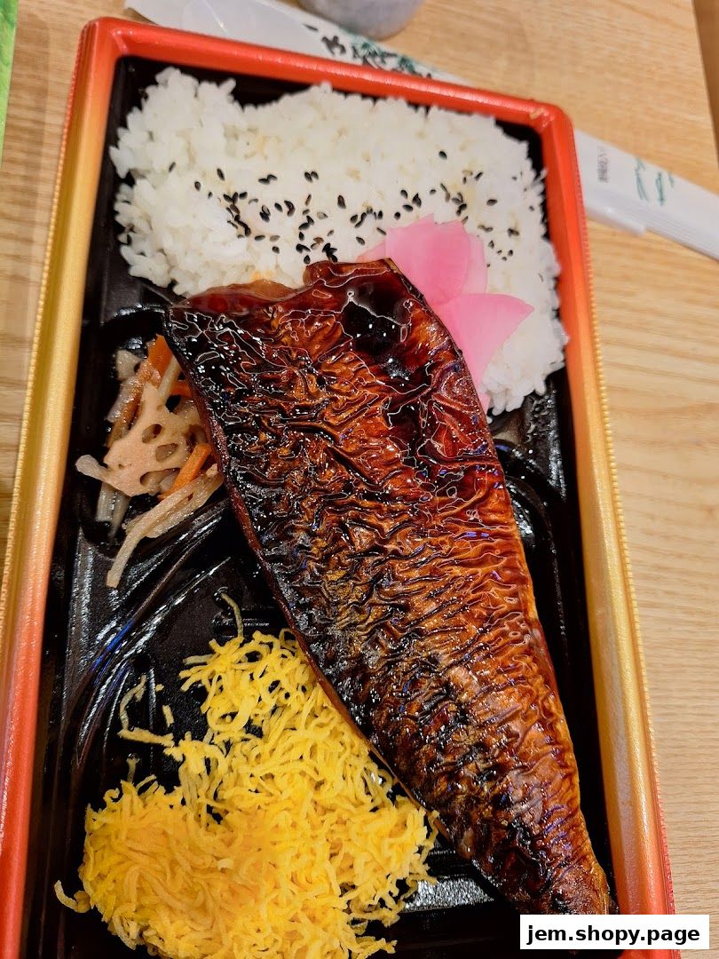A bento box featuring grilled fish, rice, and shredded egg.