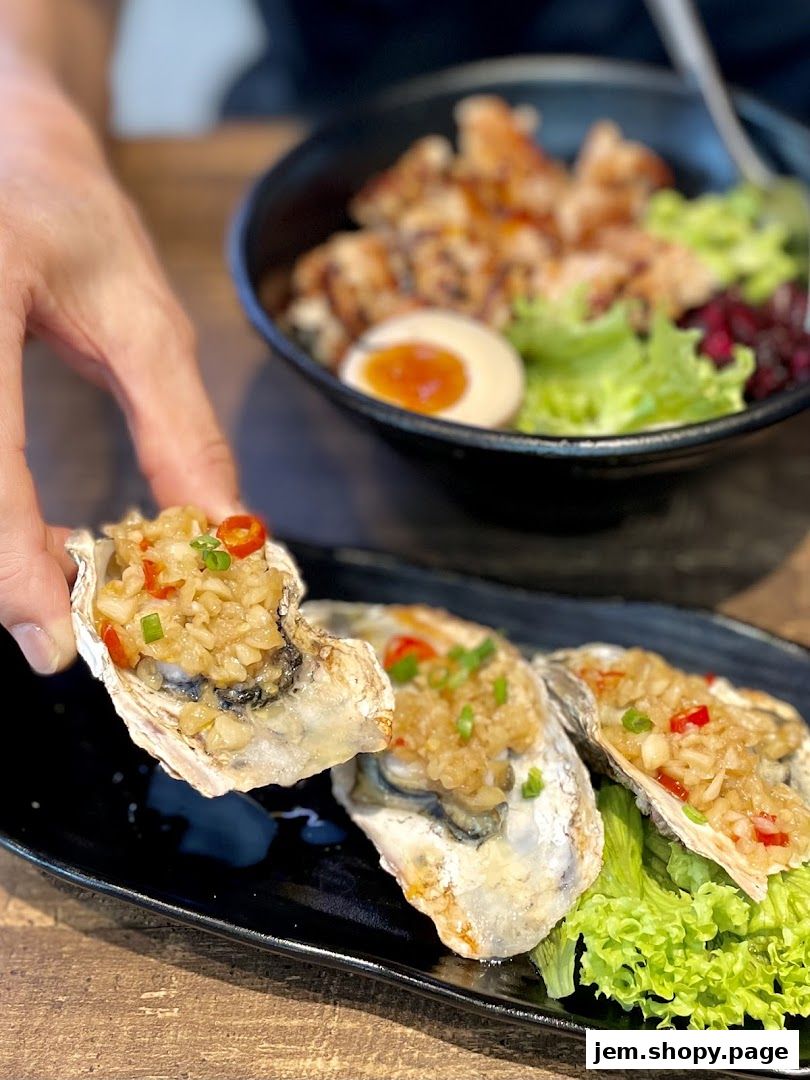 A hand picks up a freshly prepared oyster topped with garlic and chili.