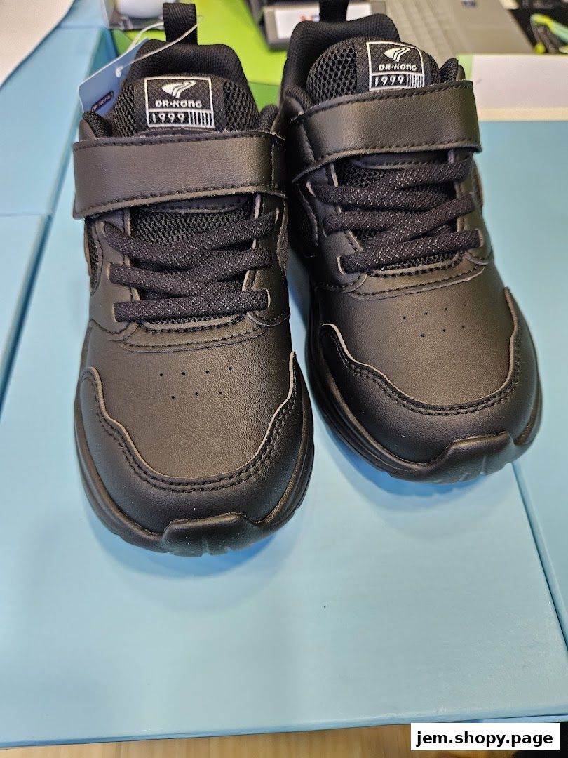 A pair of black Dr. Kong children's sneakers with velcro straps and laces.