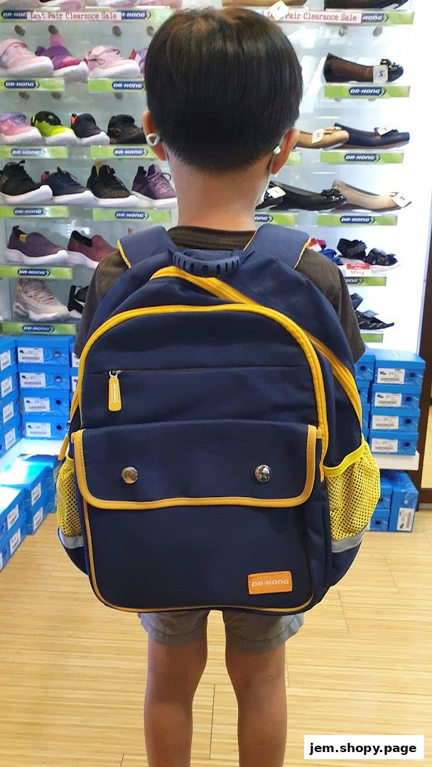 A child wearing a backpack stands in front of shelves displaying shoes at Dr. Kong.