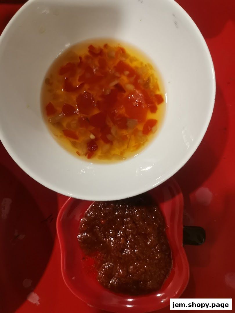 Two dipping sauces, one clear with chili and herbs, the other a dark paste.
