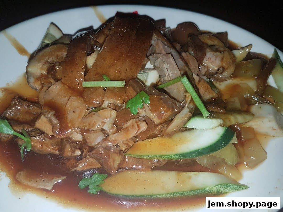A plate of braised duck with cucumber slices and sauce, garnished with spring onions and parsley.