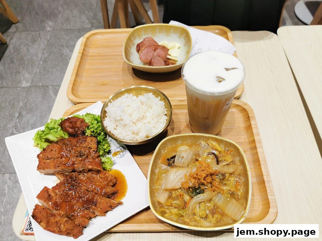 A delicious meal set with pork chop, rice, vegetables, sausage, and a drink.