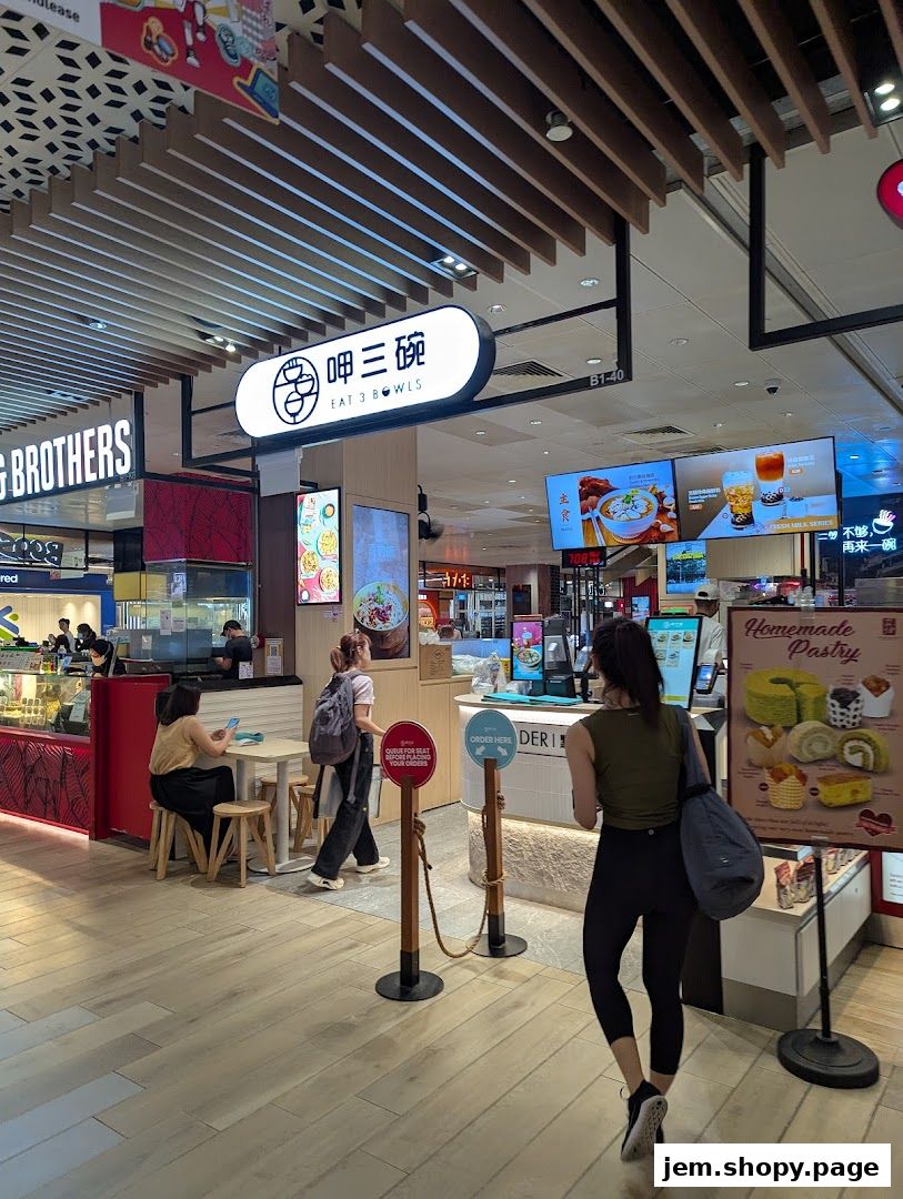 The Eat 3 Bowls shop entrance with a menu display and customers ordering.