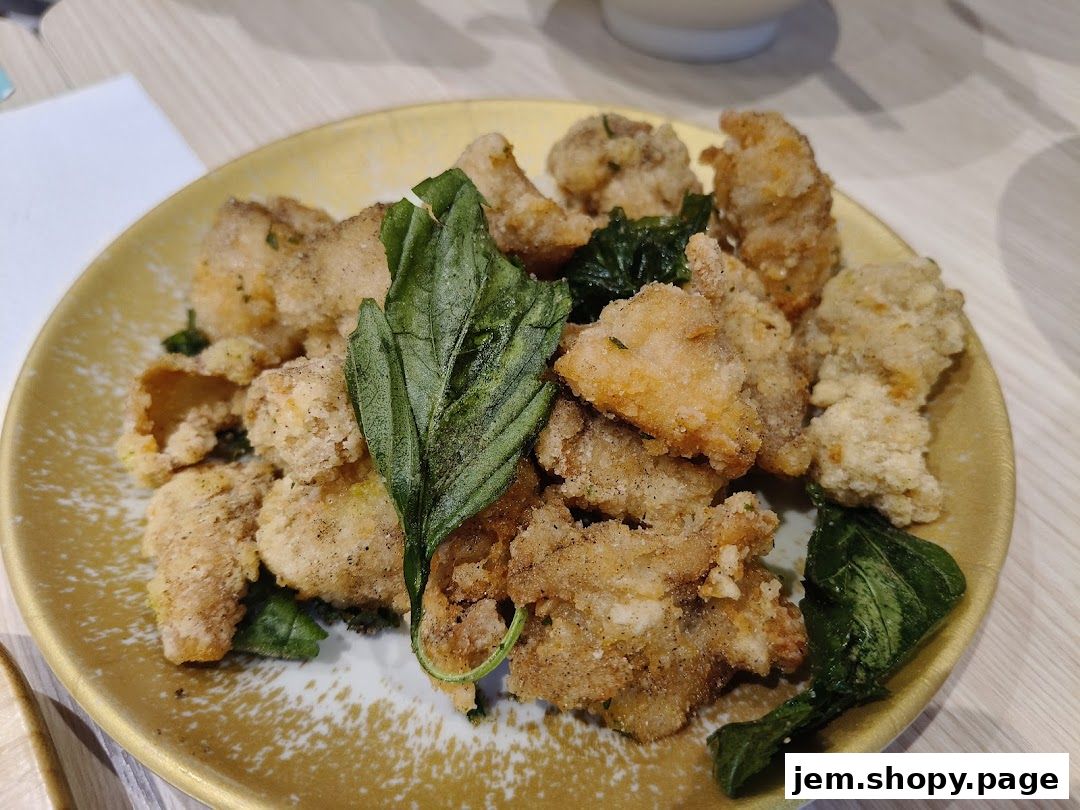 A close-up shot of a golden-brown fried chicken dish with fresh green basil leaves.
