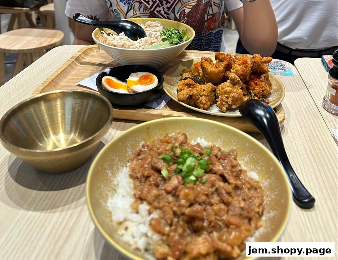 A close-up of a table with several bowls of food, including rice, fried chicken, and a soft-boiled egg.