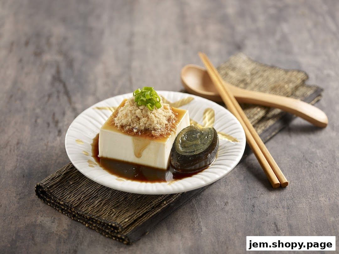 A square block of silken tofu topped with shredded meat and scallions, served with a century egg.