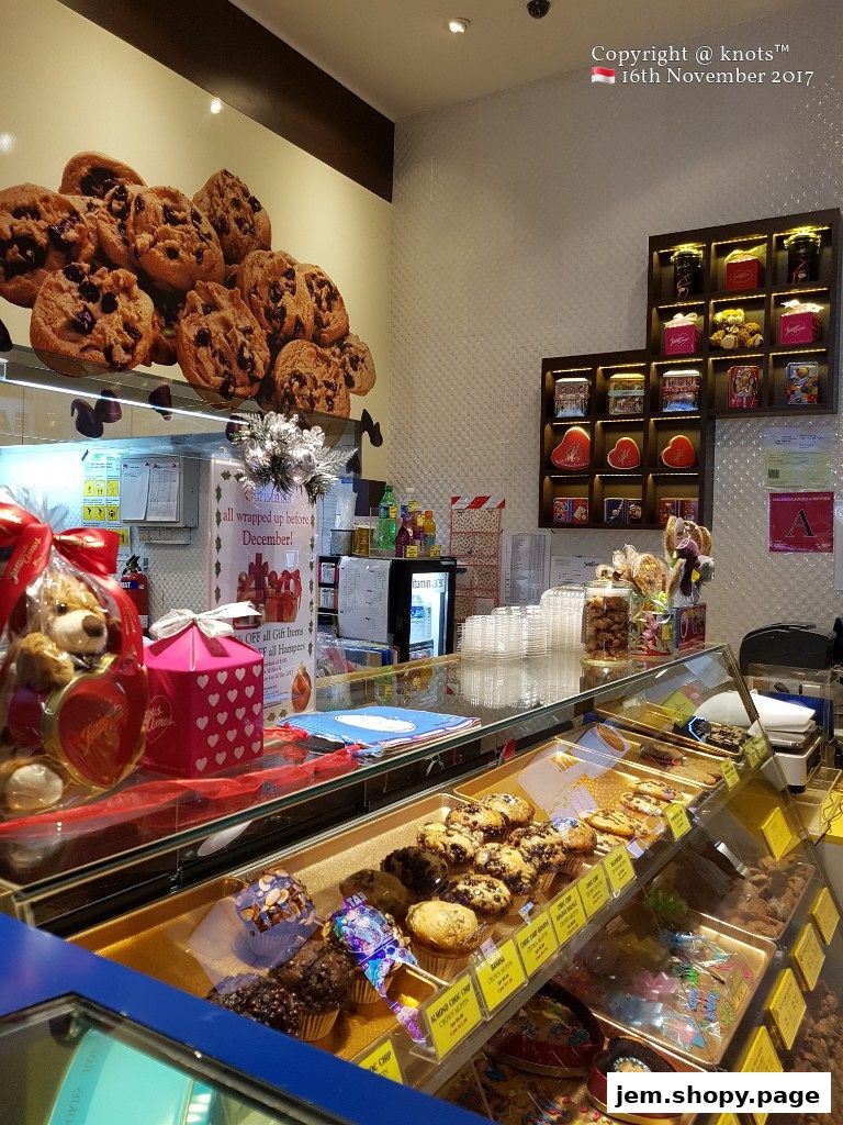 Interior view of a Famous Amos shop showcasing cookies, muffins, and gift hampers.
