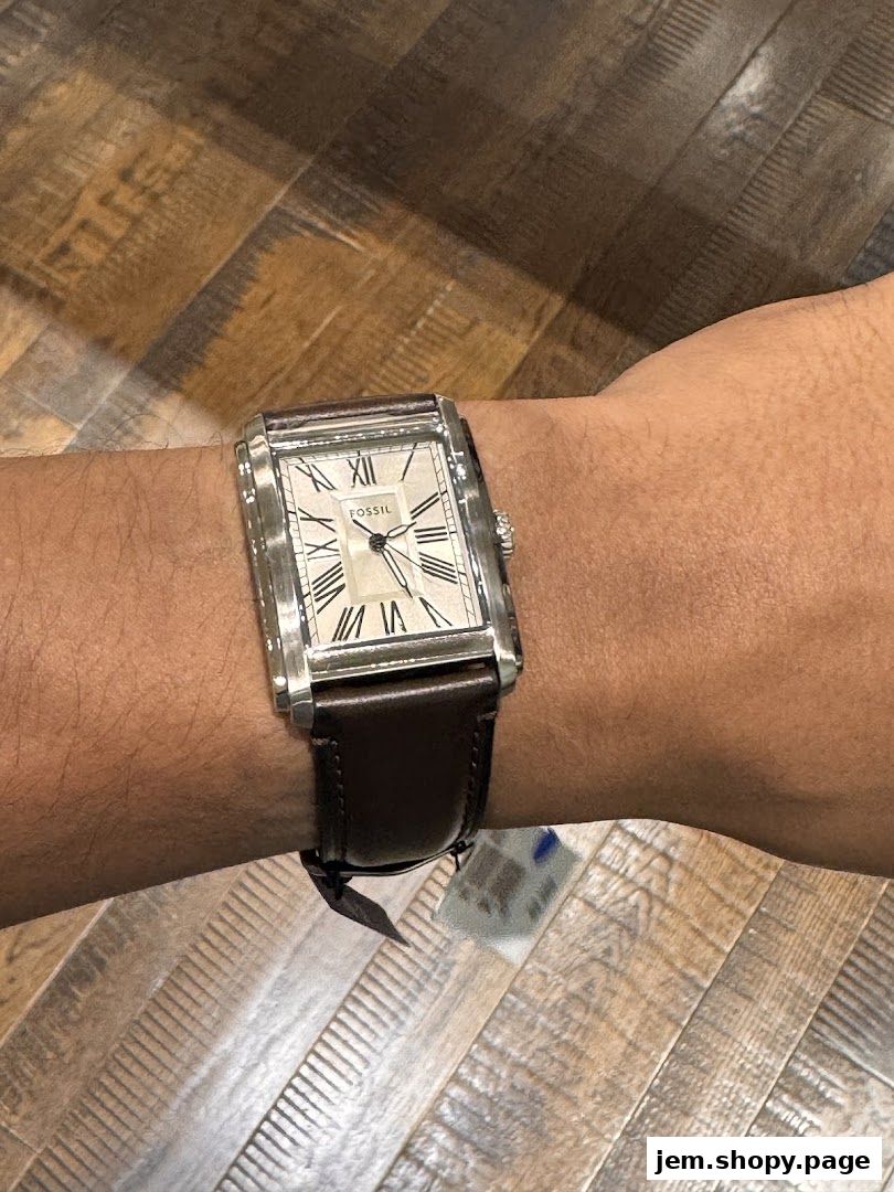 A close-up of a Fossil watch with a brown leather strap on a wrist.
