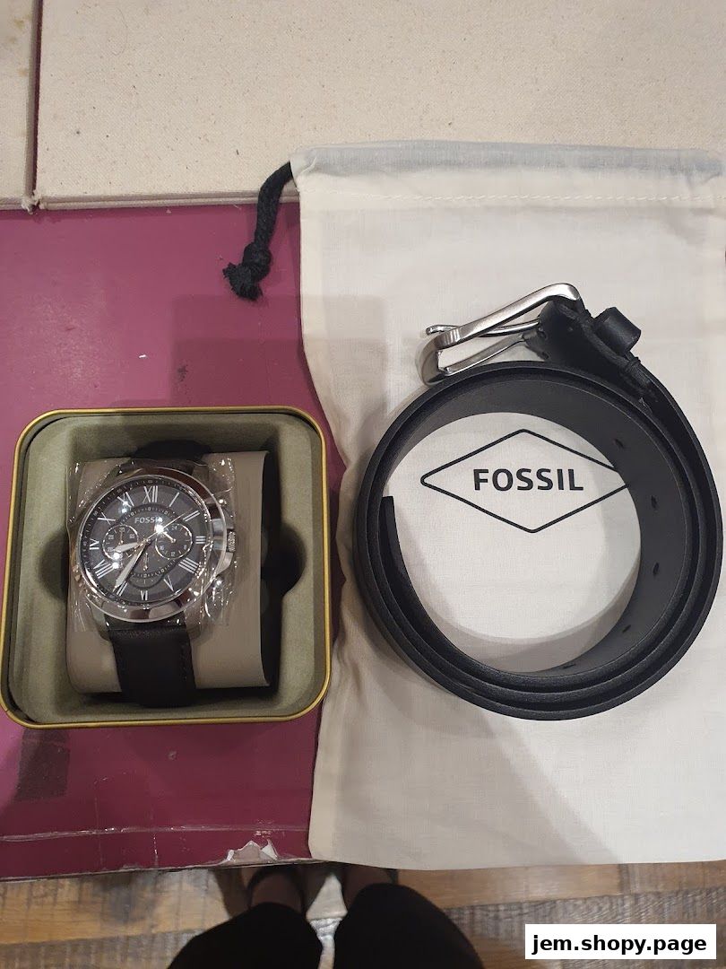 A Fossil watch in its box and a black leather belt with the Fossil logo.
