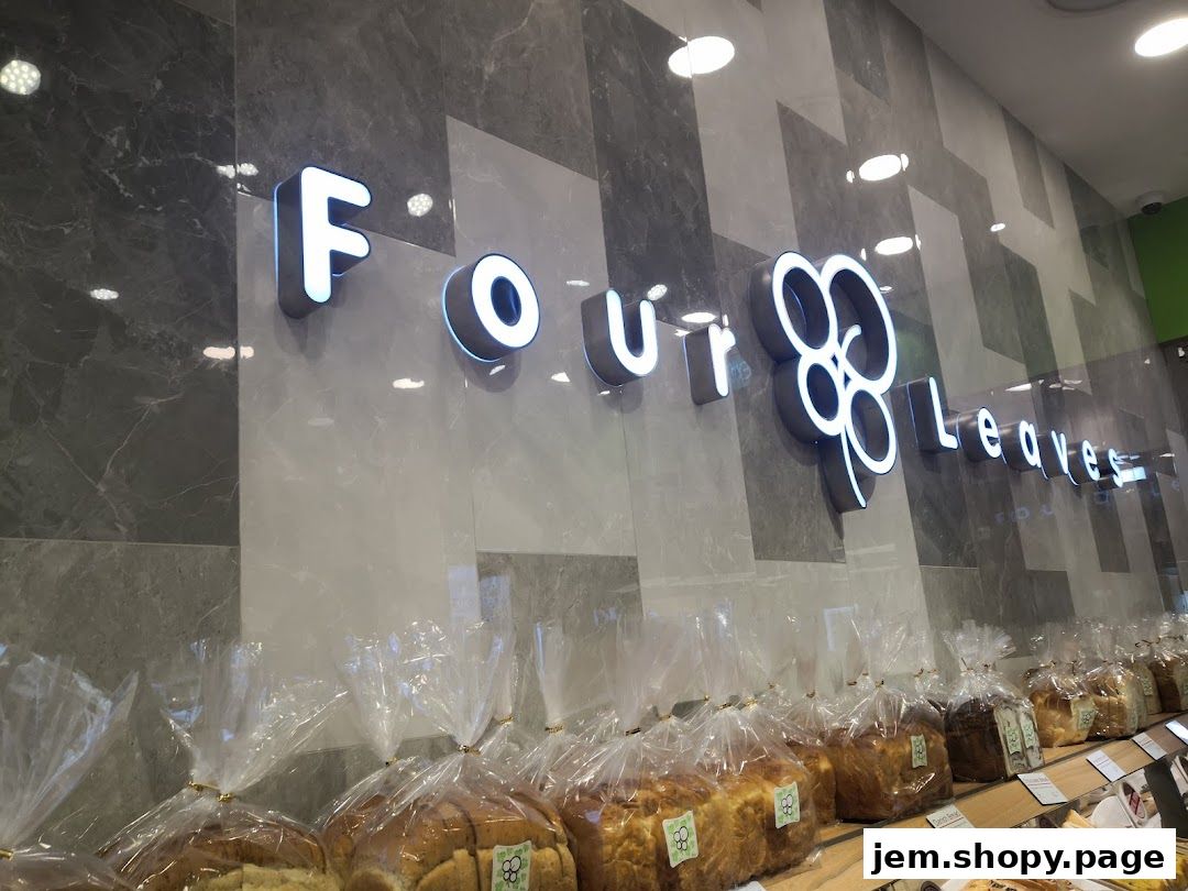 The illuminated 'Four Leaves' logo above a display of freshly baked bread loaves.