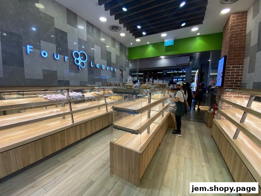 Interior view of a bakery with empty display shelves and a staff member.