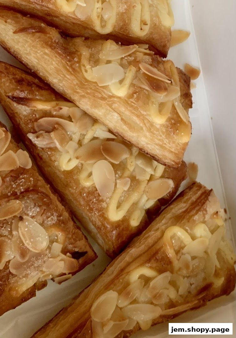 Close-up of golden-brown pastries topped with sliced almonds and cream.