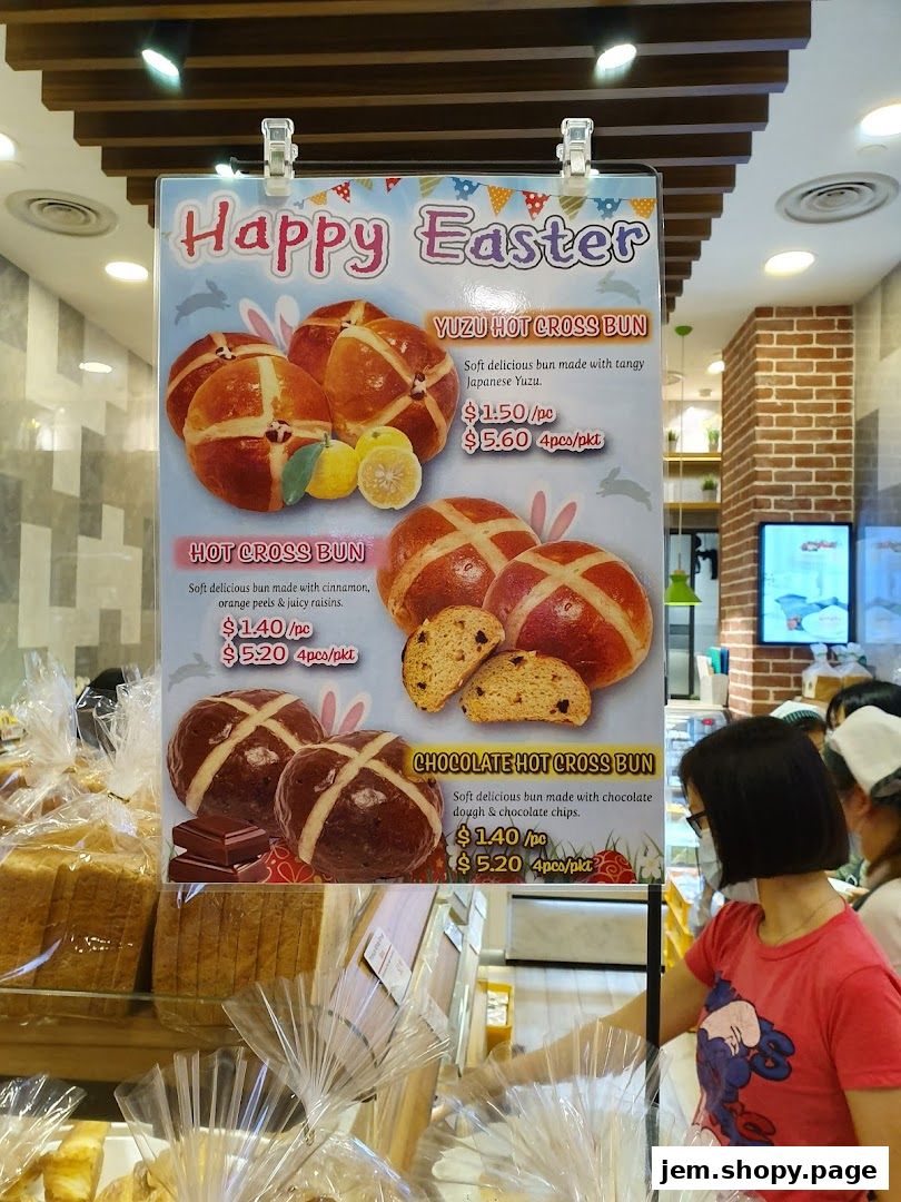 A sign displays Easter-themed hot cross buns with prices and descriptions.
