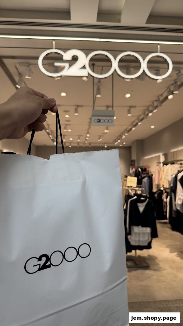 A hand holds a G2000 shopping bag in front of the store.