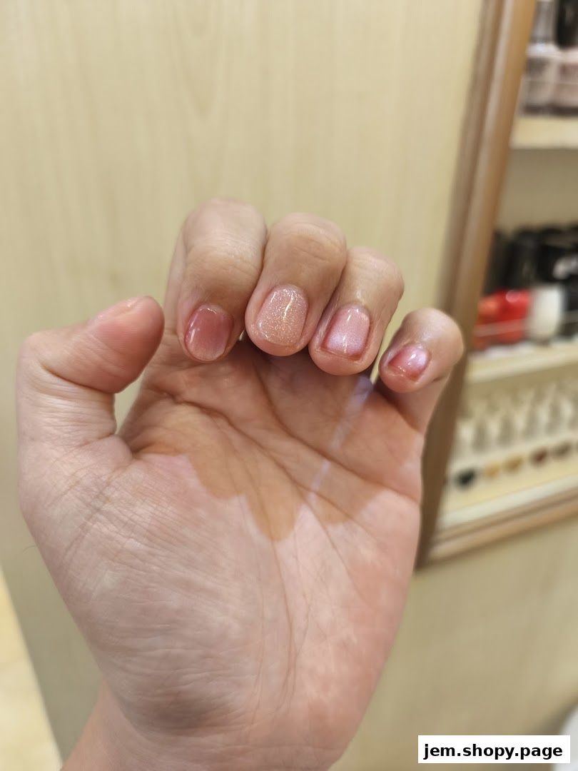A hand with freshly manicured nails in soft pink and glittery shades.