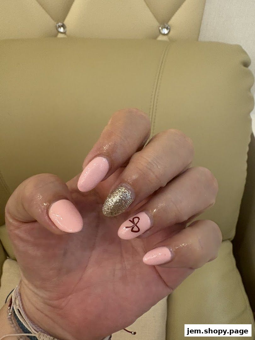 A hand with neatly done pink and glittery nails, featuring a small bow design.