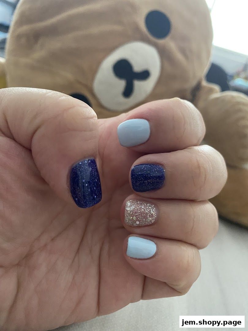 A hand with a fresh manicure featuring blue and glitter nail polish.