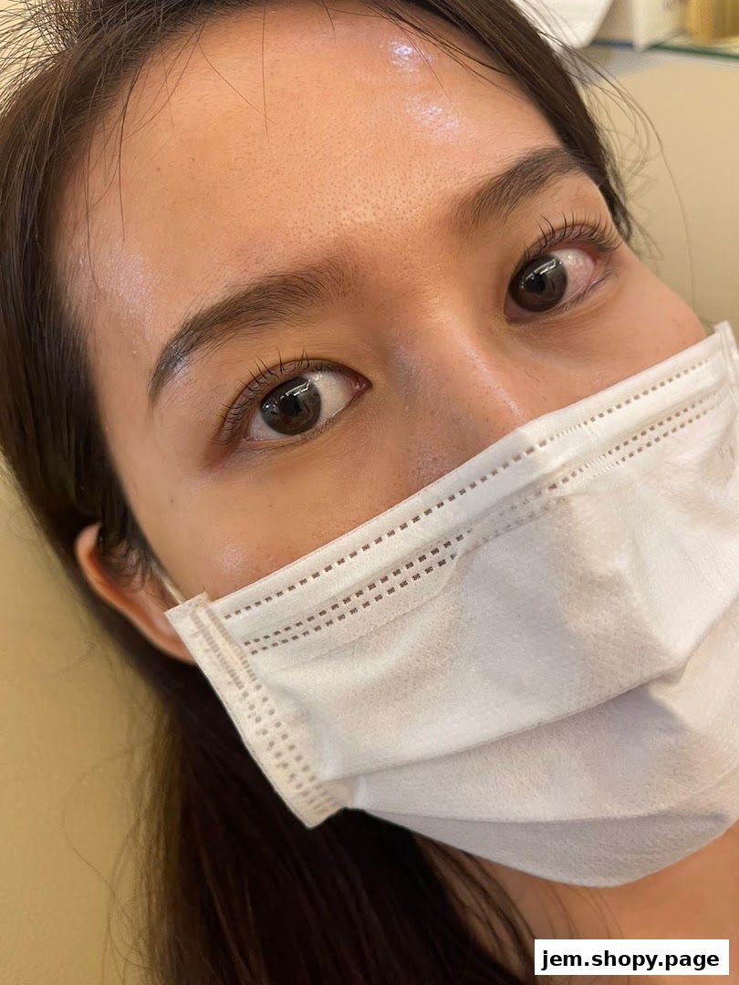 Close-up of a woman's eyes and face, wearing a white face mask.