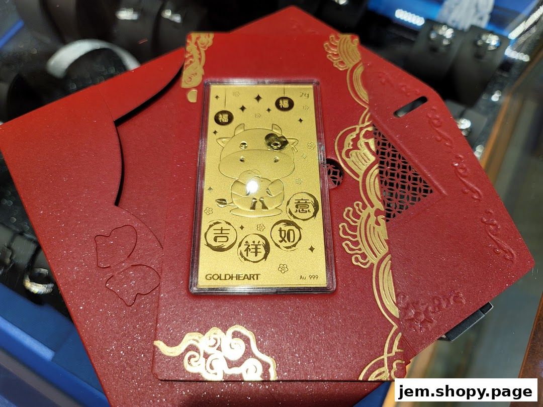 A gold bar with a cow design rests on a red envelope with gold accents.