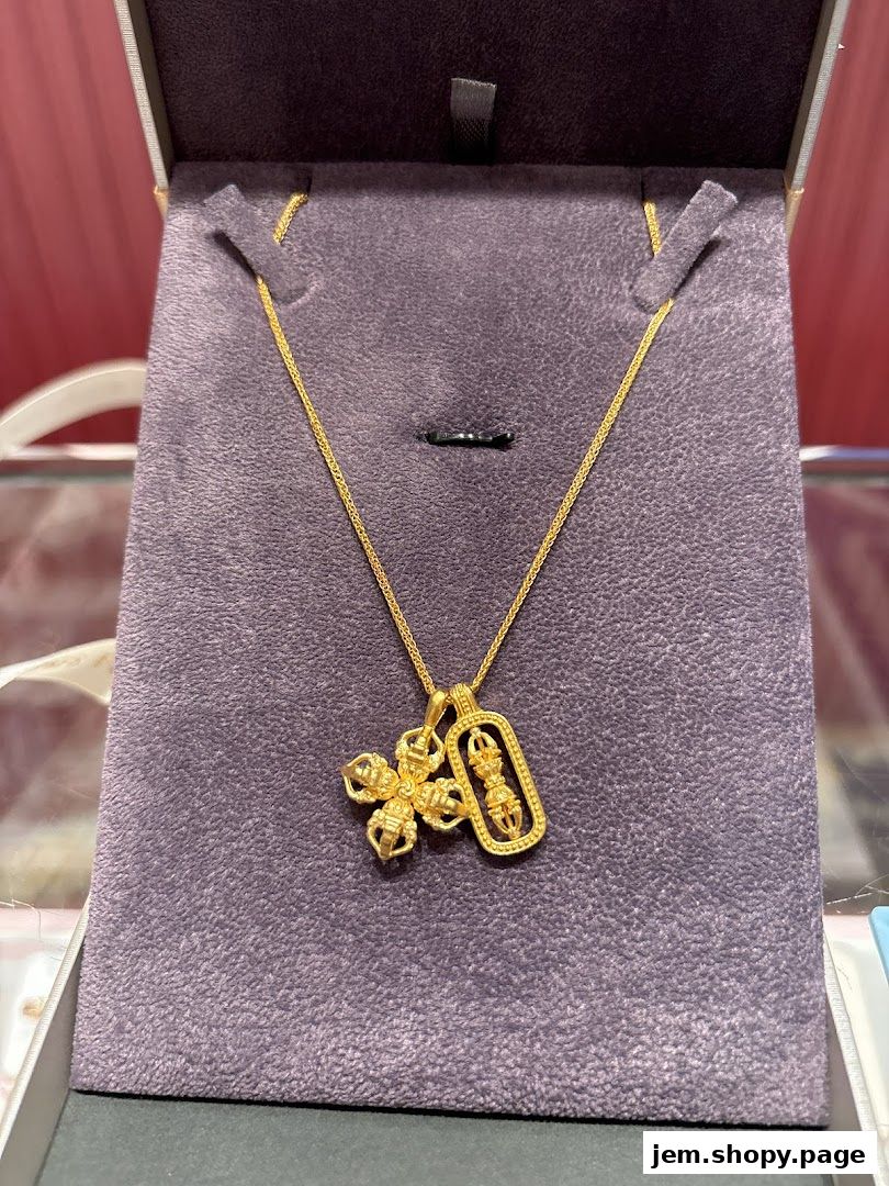 A gold necklace with two intricate pendants displayed in a jewelry box.