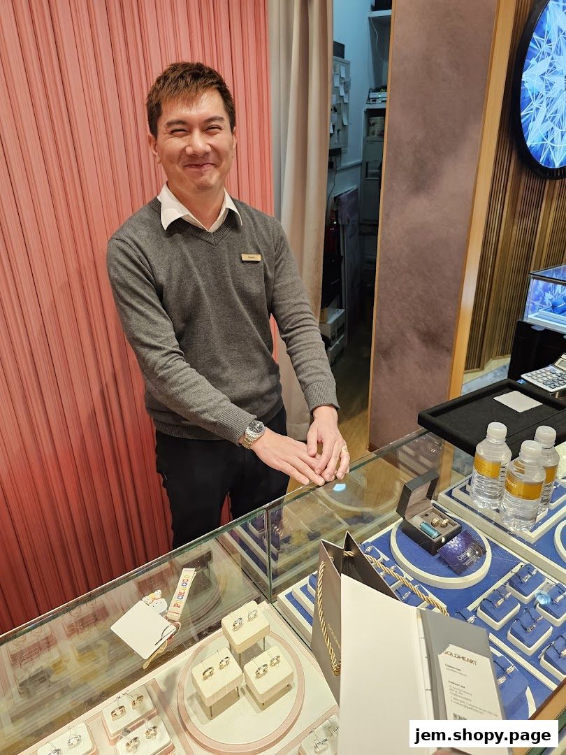 A smiling male employee stands behind a jewelry display counter at Goldheart Jewelry.