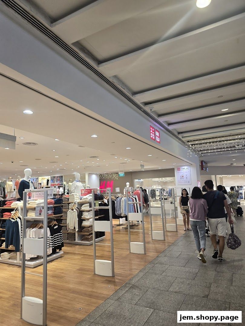 Interior view of a brightly lit clothing store with mannequins and racks of apparel.