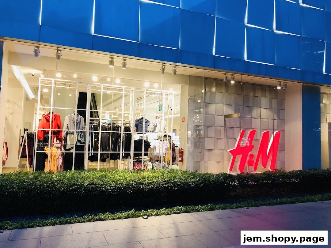 The exterior of an H&M clothing store with a large illuminated logo and display windows showcasing apparel.
