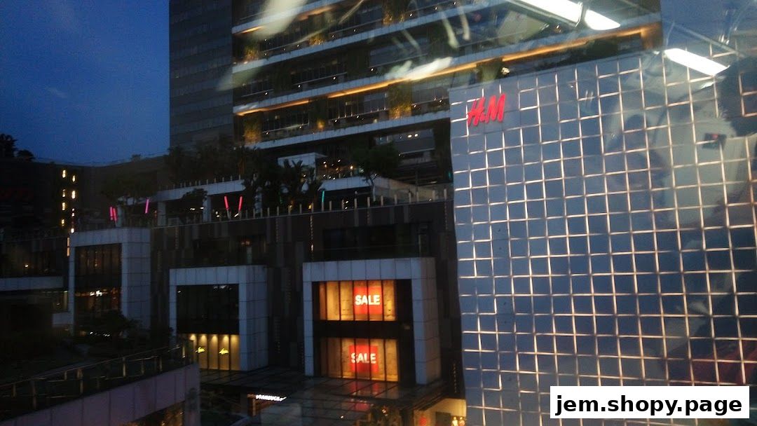 The H&M store front at dusk, with sale signs visible in the windows.