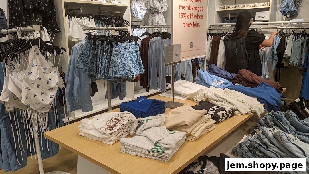 Interior view of an H&M store showcasing folded t-shirts, shorts, and jeans on display tables.