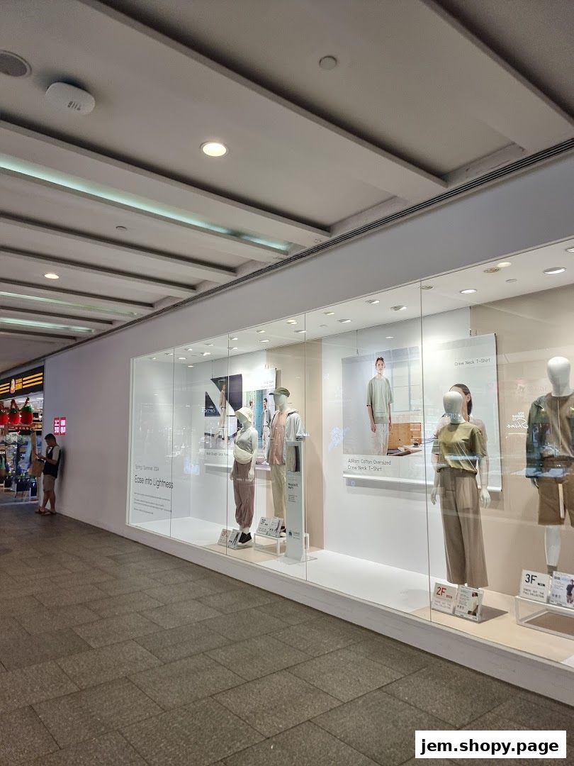 Shop window display featuring mannequins dressed in light, casual clothing.